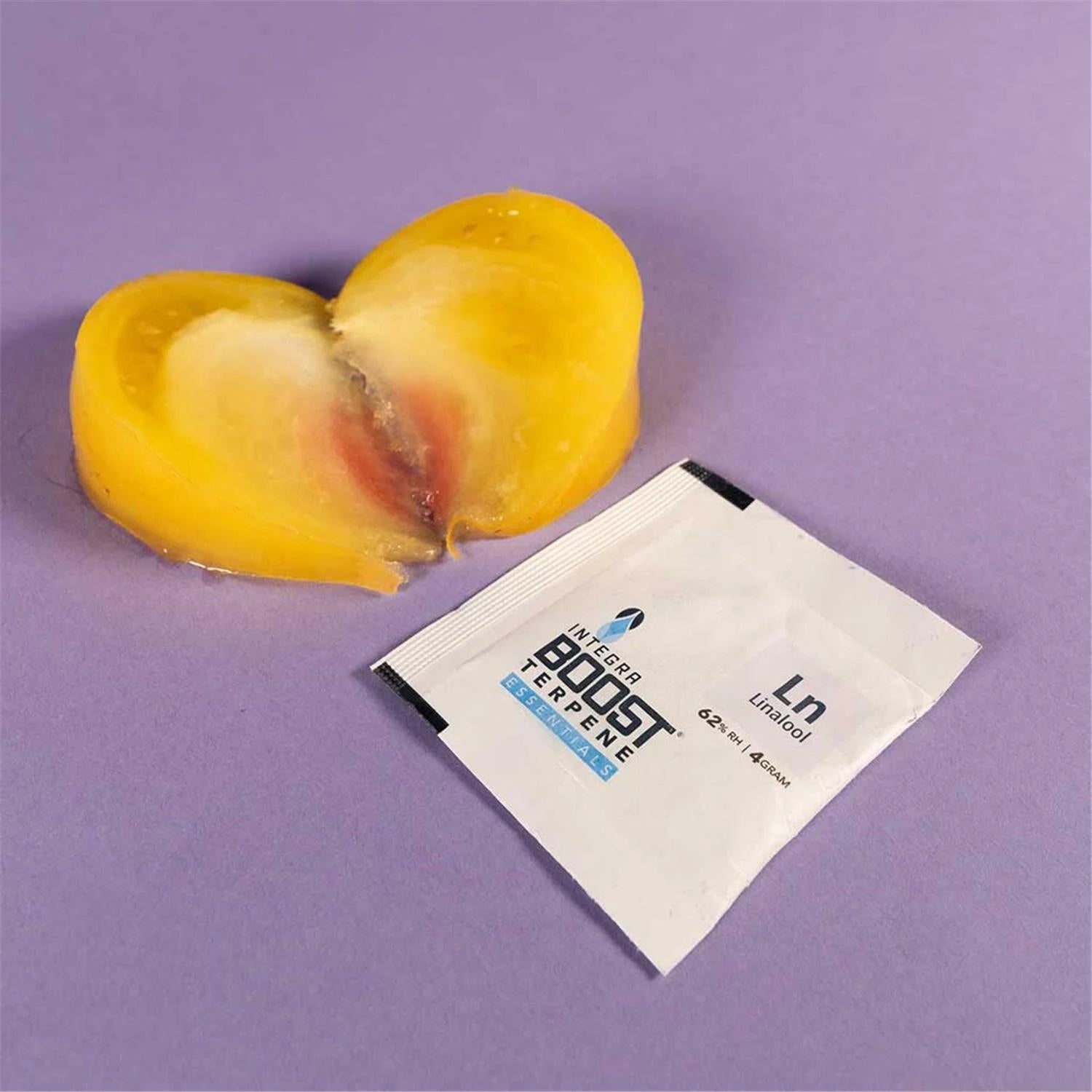 Integra Boost Terpene Essentials Linalool Ln 62% RH 4g Feuchtigkeitspad neben aufgeschnittenem Pfirsich, lila Hintergrund